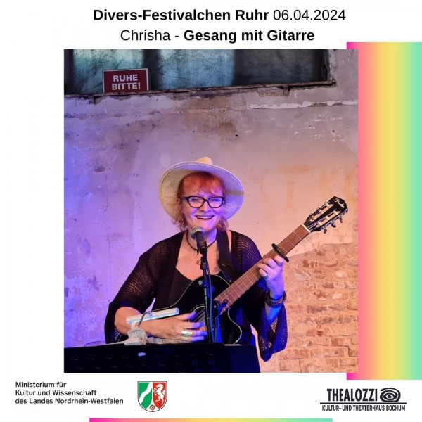Rotharige Frau mit schwarzer Brille und Hut sitzt auf einem Hocker, spielt dabei Gitarre und singt.